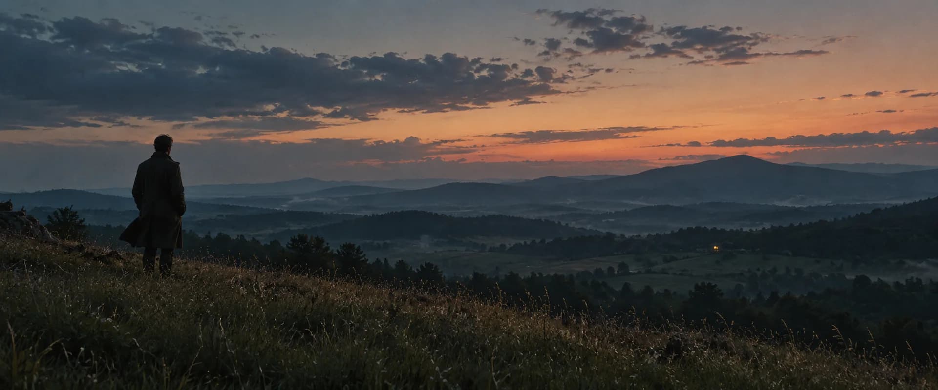 A solitary figure watches the last light fall across distant mountains